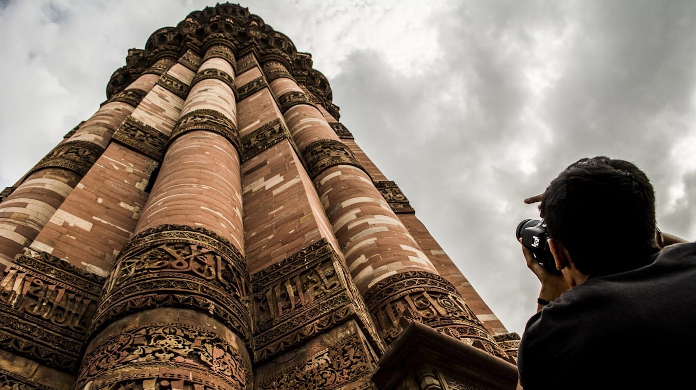 Chico haciendo foto del minarete de Qutub Minar en Delhi Minarete Qutub Minar